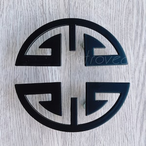 May include: Black metal cabinet knob with a circular design featuring a traditional Chinese symbol. The knob is a decorative accent for furniture.