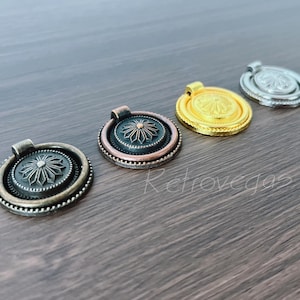 May include: Four decorative cabinet pulls in bronze, copper, gold, and silver. Each pull features a circular design with a central floral pattern and a small handle. They are displayed on a wooden surface.