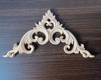 May include: A light-colored, carved wooden decorative architectural element. The design features symmetrical scrollwork and leaf details, creating an ornate, elegant appearance. The piece is likely for home decor or furniture embellishment.