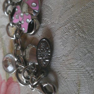 Puede incluir: Pulsera de abalorios plateada con un dije de hongo rosa y blanco, detalles de cristal transparente y un cierre de mosquet&oacute;n. La pulsera tambi&eacute;n presenta un peque&ntilde;o dije ovalado con texto.