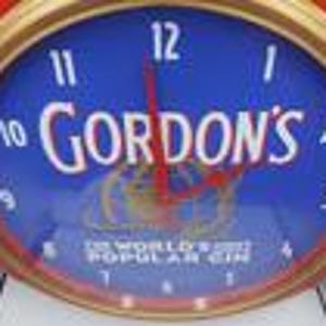 May include: A close-up of a clock with a blue face and the text "GORDON'S" in white. The clock has a gold-colored bezel and red hands. The text "THE WORLD'S MOST POPULAR GIN" is at the bottom of the clock face.