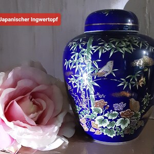 Könnte beinhalten: Eine kobaltblaue Ingwerdose mit Deckel, verziert mit einem gemalten Design eines Vogels auf einem Bambuszweig. Die Dose hat goldene Akzente und florale Details. Der Text "Japanischer Ingwertopf" befindet sich in einem roten Rechteck.