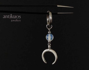 May include: A silver hoop earring with a blue and white striped bead and a crescent moon charm hanging from it.
