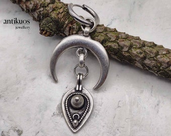 May include: Silver crescent moon earring with a teardrop-shaped pendant featuring a textured circle and bead accents.