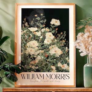 Może przedstawiać: Oprawiony wydruk artystyczny przedstawiający kwiatowy wzór z dużymi, kremowo-białymi kwiatami na ciemnym tle. Wydruk jest oznaczony "WILLIAM MORRIS" z tekstem "Transform the world with beauty" poniżej.