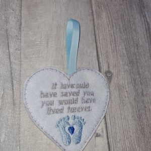 Op de afbeelding: Lichtblauw hartvormig ornament met geborduurde tekst: "Als liefde je had kunnen redden, zou je voor altijd hebben geleefd." Voorzien van twee babyvoetjes en een blauw hart. Inclusief lichtblauw lint om op te hangen.