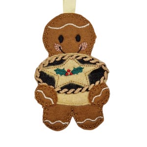 May include: A gingerbread man Christmas decoration with a star design. The brown felt ornament has a smiling face and holds a star with black, beige, and green accents. A gold ribbon is attached for hanging.