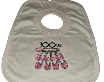 May include: White baby bib with a neck opening. The bib features the embroidered text "100% DADDIE" in pink, with the word "DADDIE" spelled out on pink safety pins.