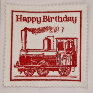 May include: A white square card with a red embroidered design. The design features a vintage train with the words "Happy Birthday" above it. The card has a decorative, scalloped edge.