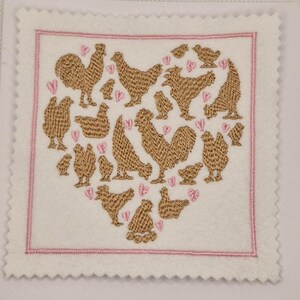 Può includere: Quadrato ricamato con una disposizione a forma di cuore di galline e galli marroni, con piccoli cuori rosa sparsi. Il disegno è su uno sfondo bianco con un bordo rosa e un bordo smerlato.