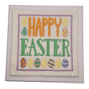 May include: A square Easter card with a cream felt design. The words "HAPPY EASTER" are embroidered in orange and green. The card is decorated with embroidered Easter eggs in various colours and patterns, including yellow, pink, and purple.
