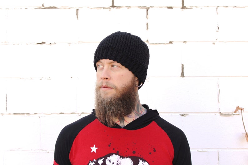 May include: A person wearing a black knitted beanie and a red and black baseball jersey with a white star and a graphic print.