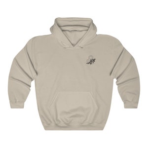 May include: A light beige hoodie with a black floral design featuring the astrological symbol for Leo.