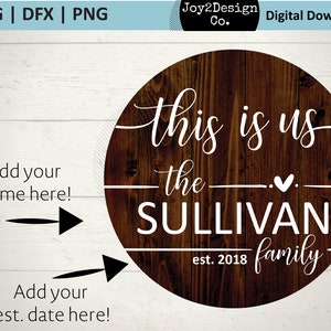 May include: A round wooden sign with the text "This is us, the SULLIVAN family, est. 2018" in white lettering. There are two blank spaces for personalisation, one for a name and one for a date.