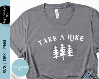 Może przedstawiać: Szary T-shirt z napisem "Take a Hike" w białym kolorze. Tekst jest otoczony kółkiem ze stylizowanym obrazem trzech sosen.