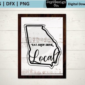 Puede incluir: Diseño gráfico en blanco y negro con el contorno del estado de Georgia con el texto "EAT. SHOP. DRINK. Local" dentro del contorno del estado. El diseño está sobre un fondo blanco con textura de madera.