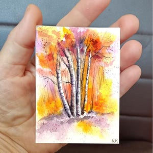 Può includere: Un piccolo dipinto rettangolare ad acquerello raffigurante un gruppo di betulle bianche con segni neri. Lo sfondo è riempito con un vibrante fogliame autunnale nei toni del giallo, arancione e rosso, con accenti viola alla base. Firmato N.P.