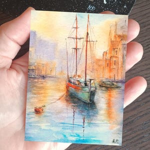 This ACEO painting (6 × 9 cm) captures a peaceful boat ride through a glowing marine, surrounded by warm architecture and reflections on water. The soft light and expressive brushwork create a romantic art.