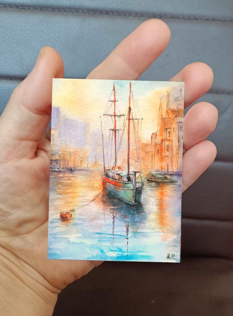 This ACEO painting (6 × 9 cm) captures a peaceful boat ride through a glowing marine, surrounded by warm architecture and reflections on water. The soft light and expressive brushwork create a romantic art.