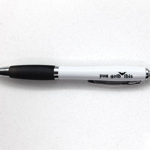 May include: White pen with a black rubber grip and the text "you goth this" printed on the barrel.