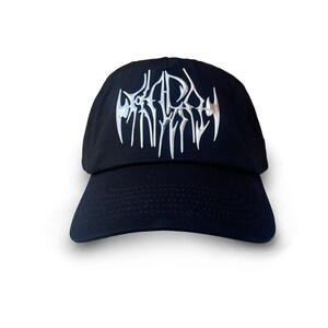 K&ouml;nnte beinhalten: Schwarze Baseballkappe mit einem silbernen gestickten Logo, das "DEAD" in einer stilisierten Schriftart zeigt.