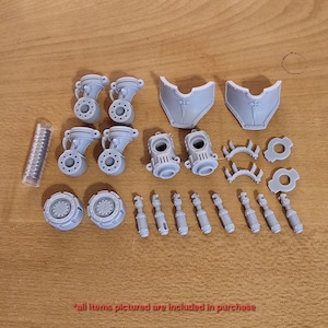 May include: A collection of unpainted grey resin miniature model parts including four jointed limb components, two curved armor plates, two cylindrical torso sections, two circular gear-like bases, eight small rods, and a clear tube of metal magnets.