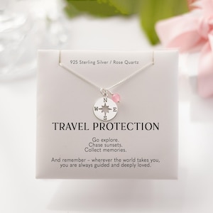 Puede incluir: Un collar de plata con un colgante de brújula y una pequeña cuenta de cuarzo rosa. El colgante tiene las letras N, W, E y S. La tarjeta dice "TRAVEL PROTECTION" e incluye texto inspirador.