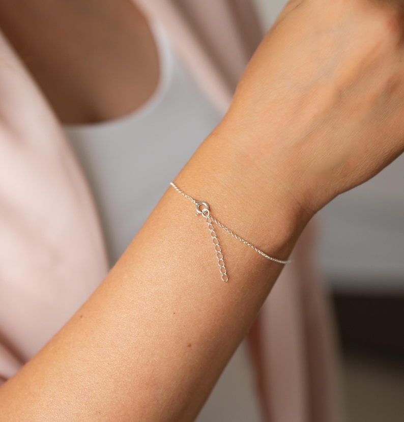 Puede incluir: Una delicada pulsera de cadena plateada con un dise&ntilde;o de eslabones met&aacute;licos finos y pulidos. La pulsera incluye un peque&ntilde;o cierre de resorte circular y una cadena extensora con eslabones circulares abiertos para ajustar el tama&ntilde;o.