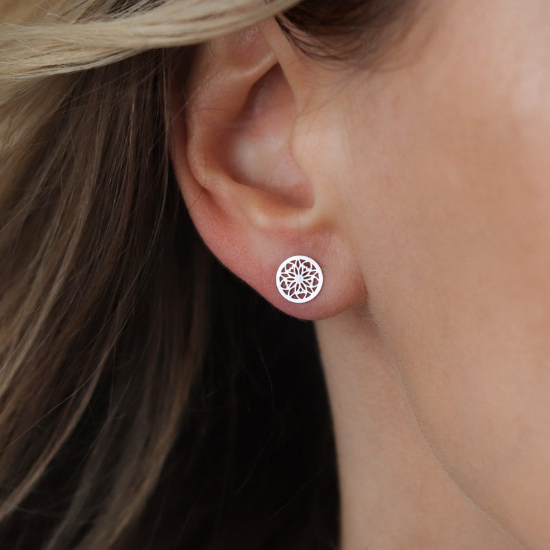 Close-up of a woman ear wearing a sterling silver stud earring with a detailed geometric design.