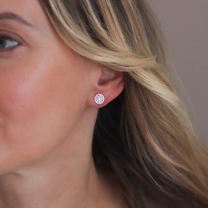 Woman wearing a delicate filigree design silver earring.