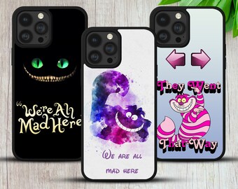 May include: Three different iPhone cases featuring the Cheshire Cat from Alice in Wonderland. The first case is black with a green Cheshire Cat face and the text "We're All Mad Here". The second case is white with a purple watercolor Cheshire Cat and the text "We Are All Mad Here". The third case is blue with a pink Cheshire Cat and the text "They Went That Way".
