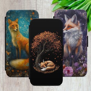 Peut inclure: Trois étuis de téléphone avec des illustrations de renards. Un étui présente un renard sur un fond floral bleu. Un autre montre un renard endormi sous un arbre avec des feuilles d'automne. Le troisième étui affiche un renard dans un cadre floral violet.