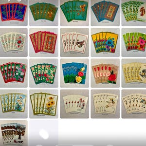 May include: A set of vintage playing cards with various designs, including flowers, animals, and landscapes. The cards are in a deck of 52 cards, with each card featuring a different design. The cards are in good condition and would be a great addition to any collection.