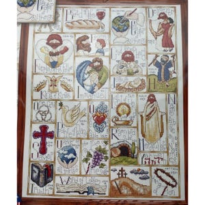 Może przedstawiać: Oprawiony haft krzyżykowy z motywami religijnymi. Dzieło przedstawia różne sceny i symbole biblijne, w tym Jezusa, gołębia, krzyż i tekst. Paleta kolorów obejmuje odcienie brązu, czerwieni i niebieskiego.