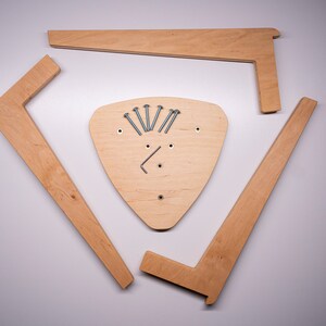 K&ouml;nnte beinhalten: Vier unfertige Holzst&uuml;cke f&uuml;r einen dreieckigen Hocker. Die Teile sind in einem Kreis um eine dreieckige Holzbasis mit Schrauben in der Mitte angeordnet.