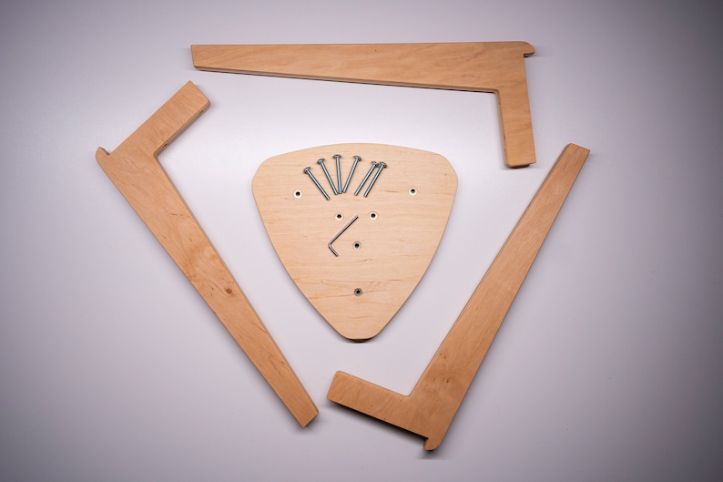K&ouml;nnte beinhalten: Vier unfertige Holzst&uuml;cke f&uuml;r einen dreieckigen Hocker. Die Teile sind in einem Kreis um eine dreieckige Holzbasis mit Schrauben in der Mitte angeordnet.
