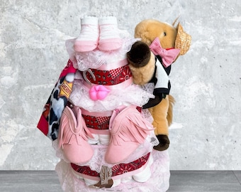 May include: A pink and red diaper cake with a stuffed horse toy, cowboy hat, and baby booties. The cake is decorated with lace and a pink bow.