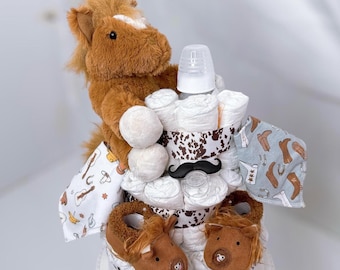 May include: A diaper cake decorated with a brown plush horse, a bottle, and cowboy-themed booties. The cake is wrapped in white and brown patterned fabric and has a brown mustache on top.