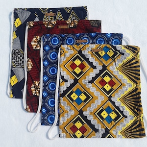 May include: Four drawstring bags with different colorful African print patterns. The bags are made of fabric and have white drawstrings. The bags are stacked on top of each other.