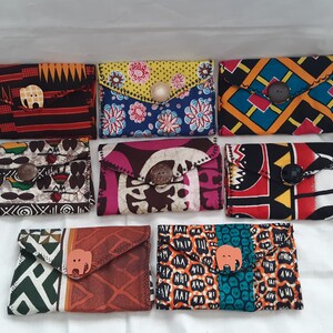 May include: Eight colourful fabric wallets with a flap closure and a wooden button. Each wallet features a different African print design.