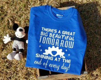 Könnte beinhalten: Ein königsblaues T-Shirt mit weißem Text, der "There's a great big beautiful tomorrow shining at the end of every day!" lautet. Der Text ist von weißen Sternen umgeben.