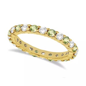 Puede incluir: Un anillo de banda de oro con piedras redondas verdes y blancas alternas.