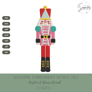 Puede incluir: Un archivo de diseño de bordado a máquina con un cascanueces colorido. El diseño incluye una chaqueta rosa, pantalones rojos y un cinturón dorado. También se ve el texto "MACHINE EMBROIDERY DESIGN FILE" y "Instant Download".