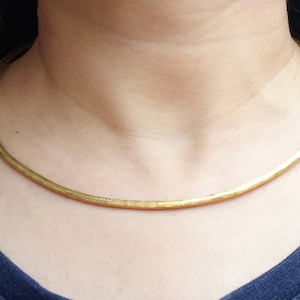 May include: A gold choker necklace with a hammered finish. The necklace is simple and elegant, and would make a great addition to any jewellery collection.