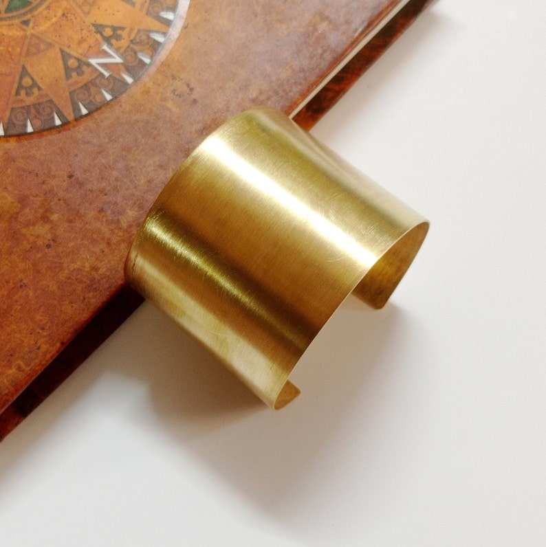 Peut inclure: Un bracelet jonc en m&eacute;tal dor&eacute; poli. Le bracelet est fait d'une seule pi&egrave;ce de m&eacute;tal pli&eacute;e en cercle.