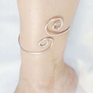 Puede incluir: Tobillera de plata con un diseño de doble espiral.