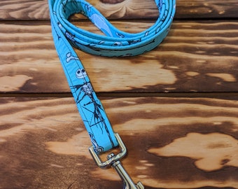 May include: A turquoise dog leash featuring a repeating pattern of a skeleton, bones, and other spooky elements. The leash has a silver metal clasp and is made of a durable fabric. The leash is designed for pet owners.