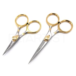 May include: Two pairs of gold and silver scissors with the text "DR. SLICK" on the blades. The scissors have gold finger holes and a gold screw in the center. The blades are silver and pointed.