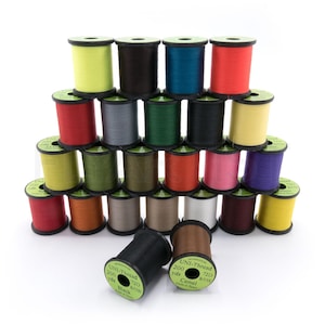 May include: A collection of colorful spools of UNI-Thread, stacked in a pyramid formation. The spools display a variety of colors, including yellow, black, teal, red, and pink. Each spool is labeled with "UNI-Thread" and "200 yds".