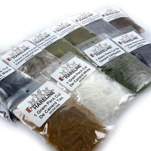 May include: A collection of Hareline brand fly tying materials in clear plastic packaging. The packages contain various colors of feathers, including black, tan, olive, white, and grey. Each package is labeled with the product name and weight.